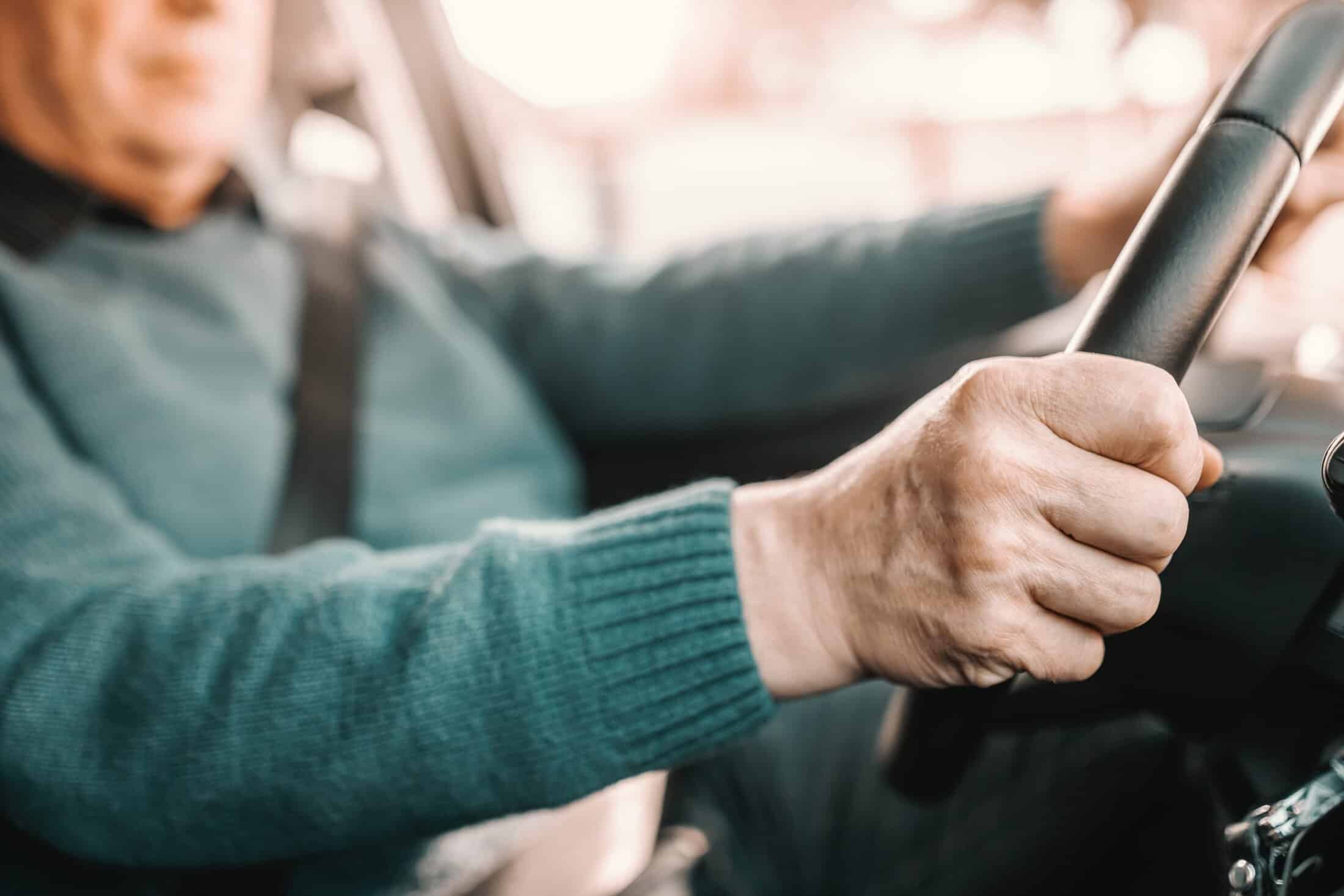 Older male driver behind wheel of car