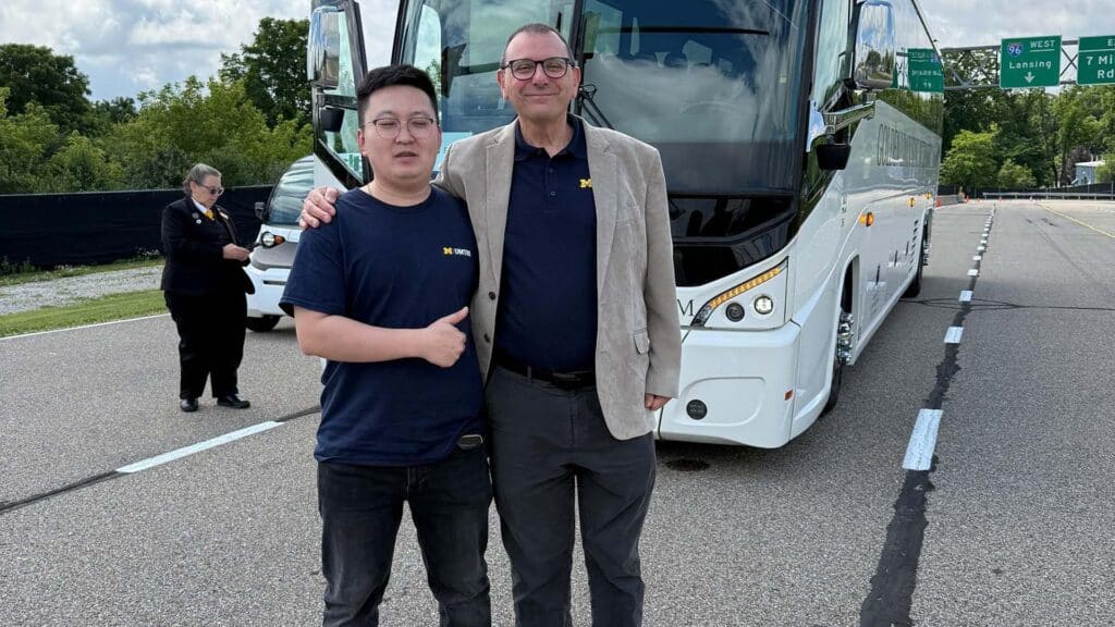 Yilin Wang and Andrew Donaldson stand in front of a research vehicle at the Mcity Test Facility